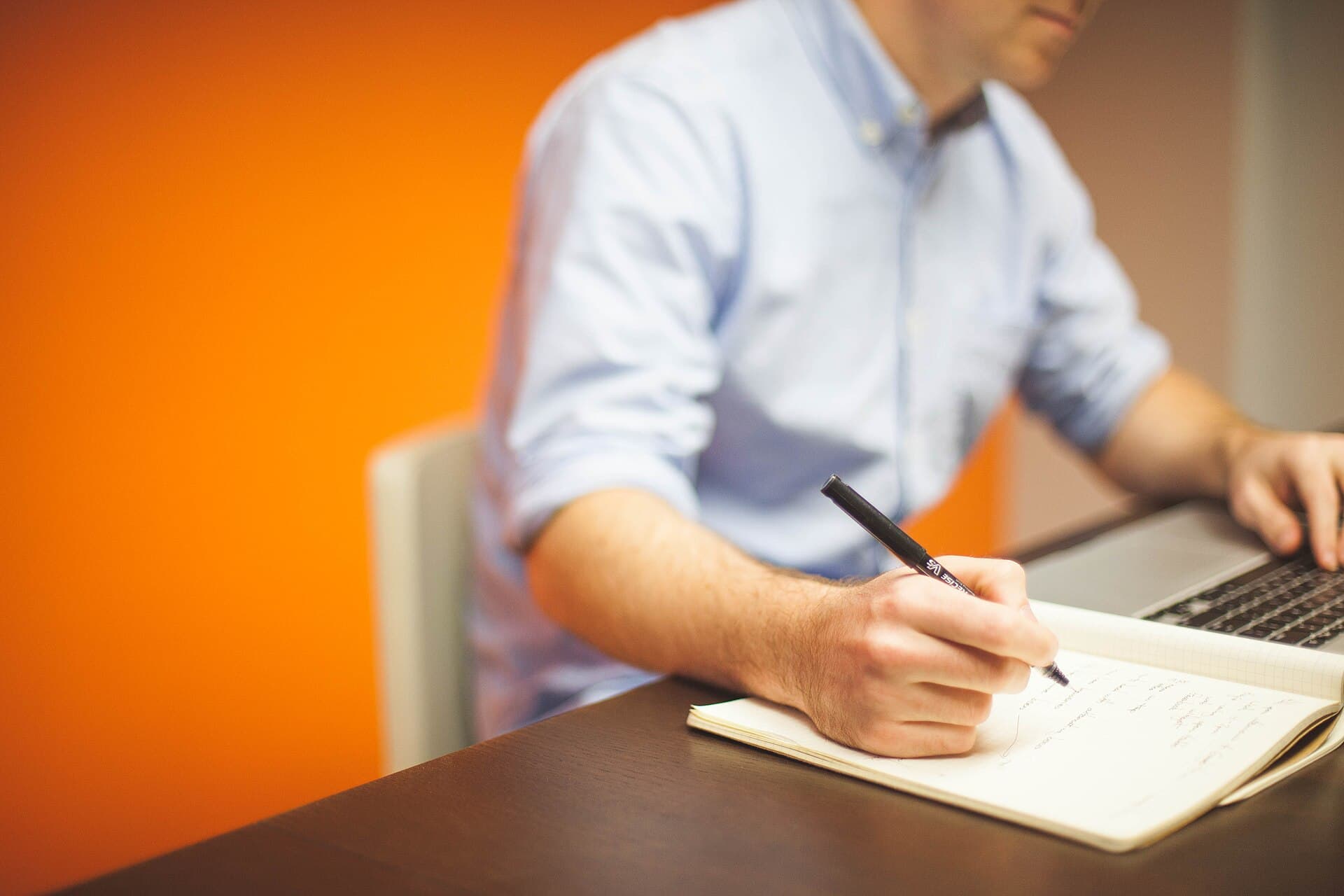 Man writing while using his laptop 2