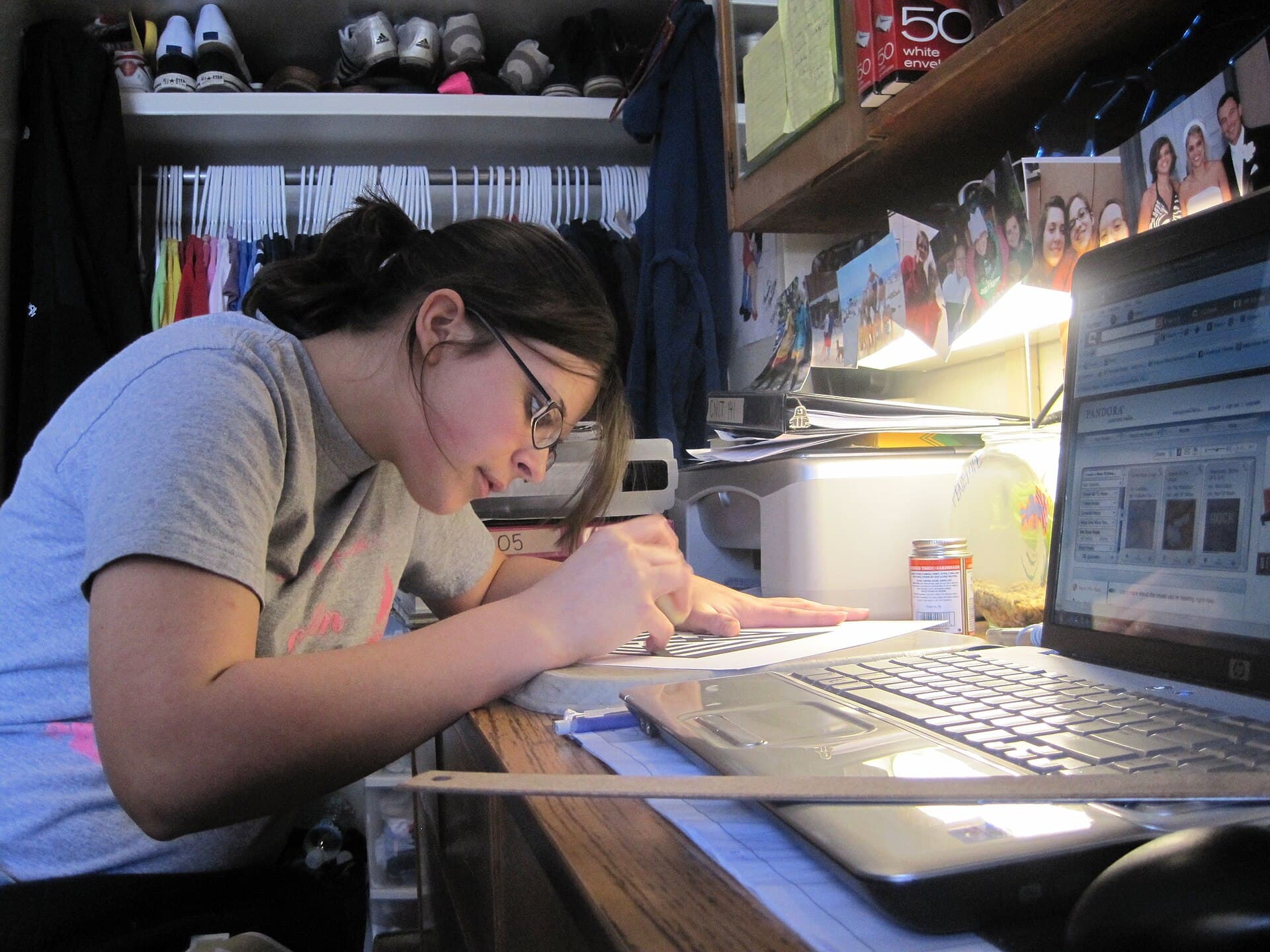 Female student writing and studying at dorm room desk
