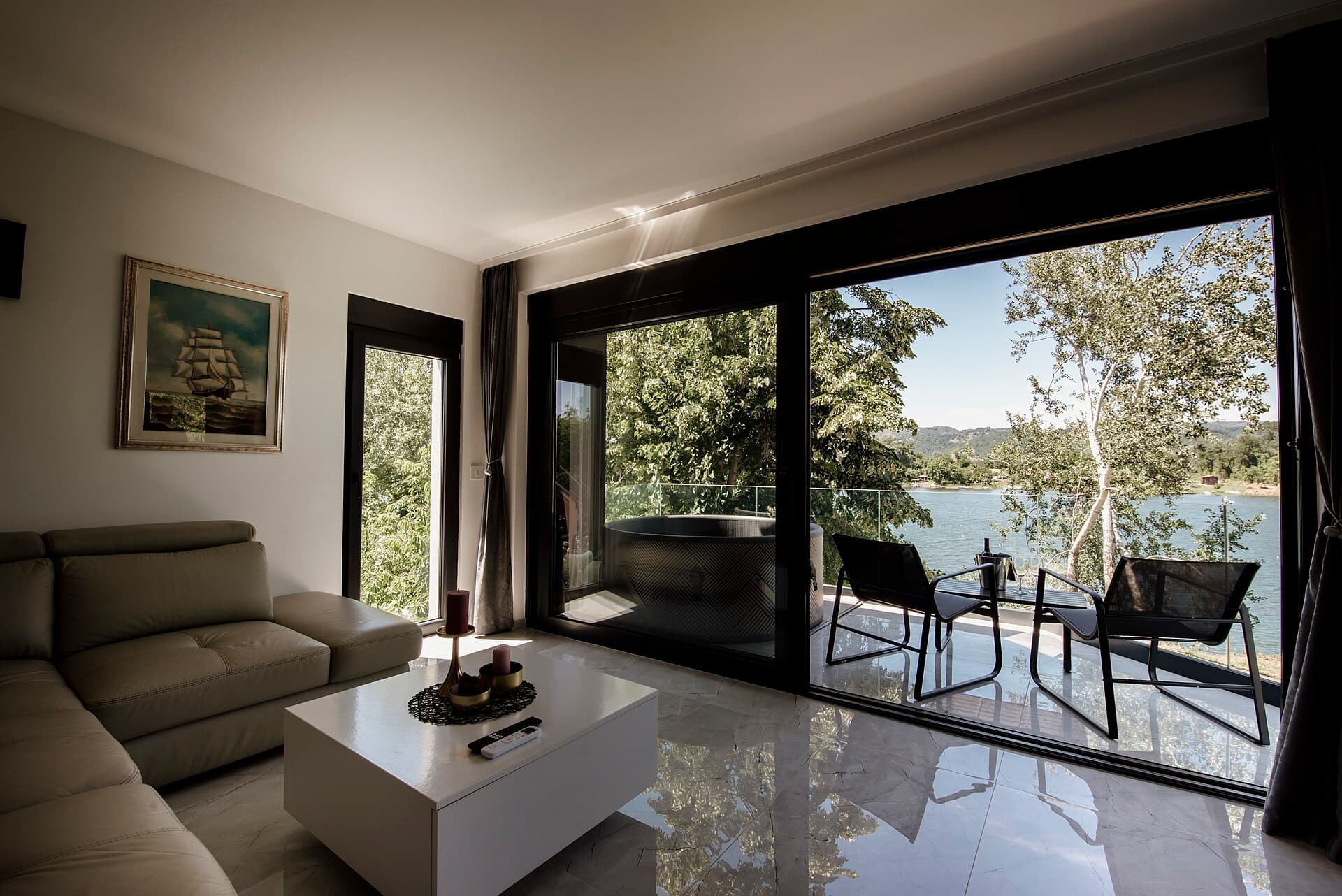 Cozy living room with a view of the lake and trees in the background at midday