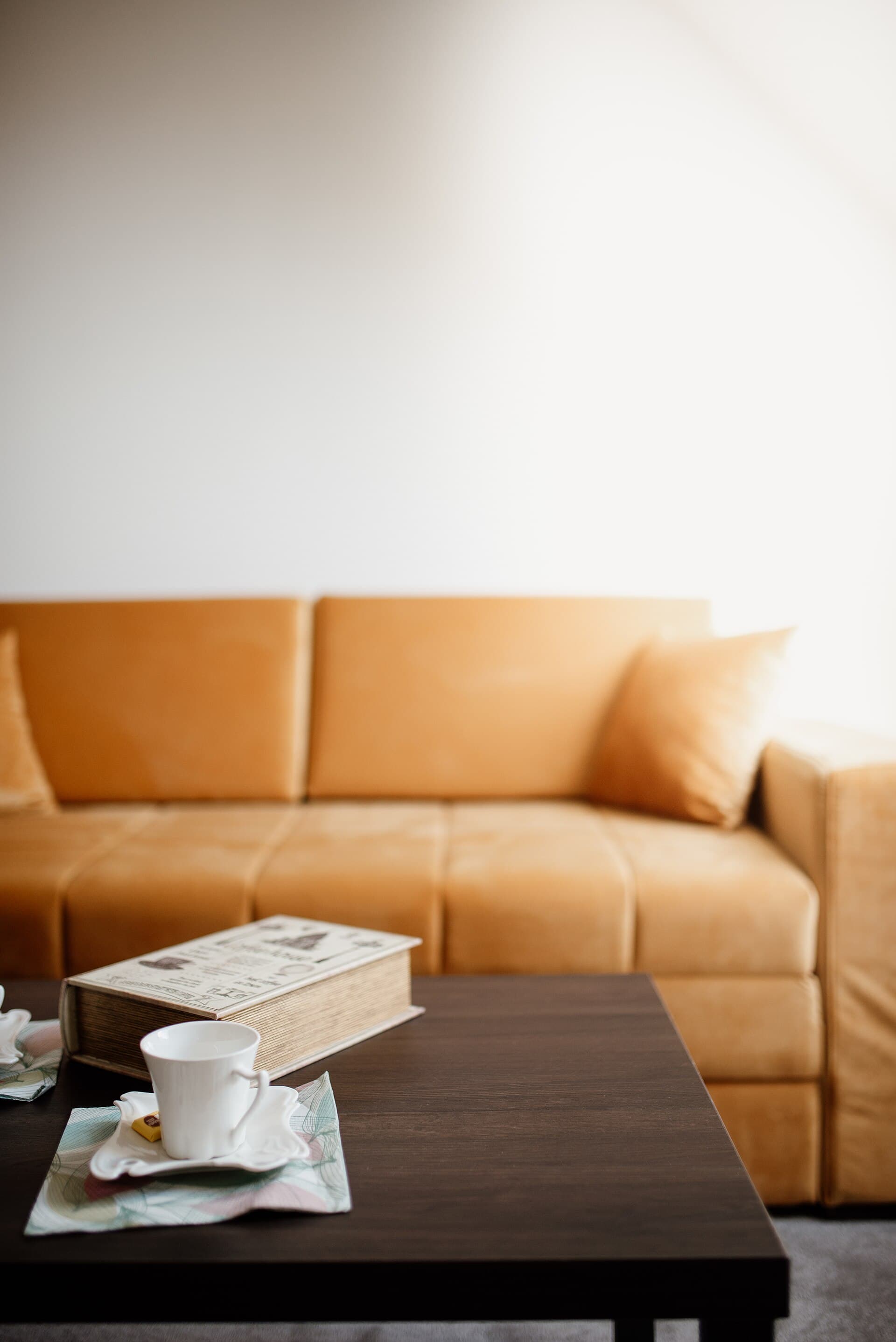 Cozy living room setup with a warm sofa, coffee cup, and an open book in a softly lit environment