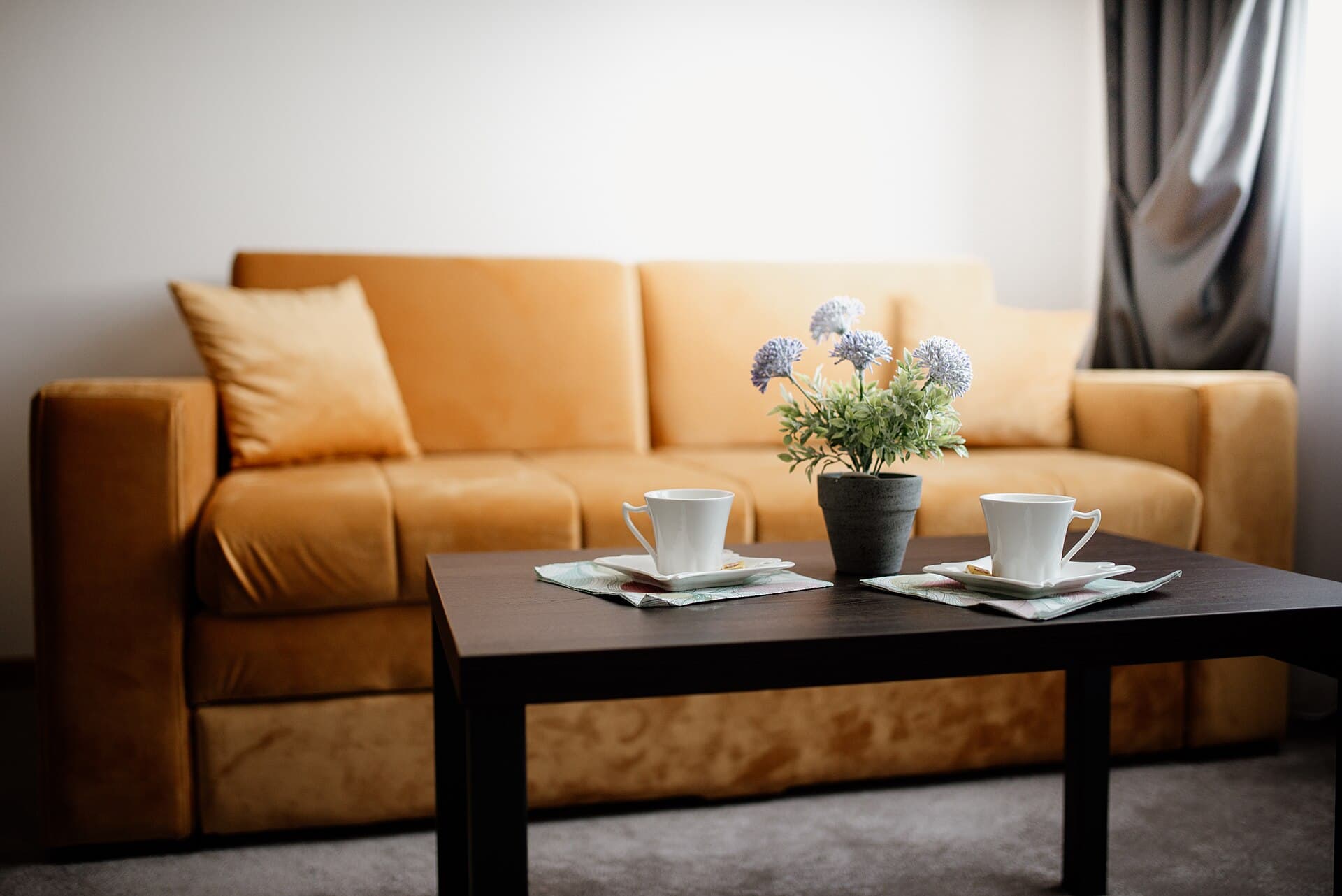 Cozy living room setting with a yellow sofa and a coffee table adorned with cups and a flower pot